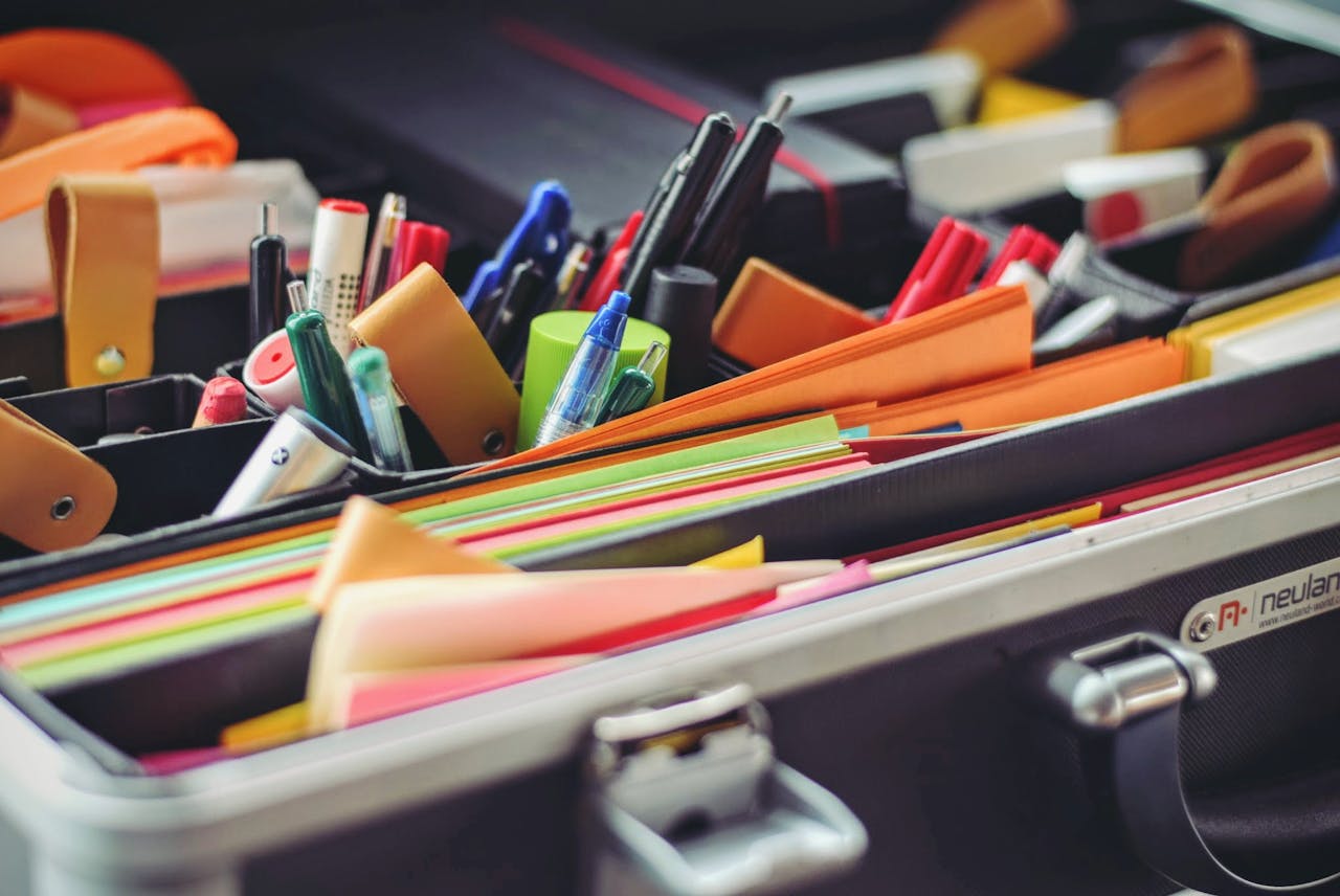 A collection of colorful office supplies neatly arranged in a suitcase, perfect for professionals on the go.